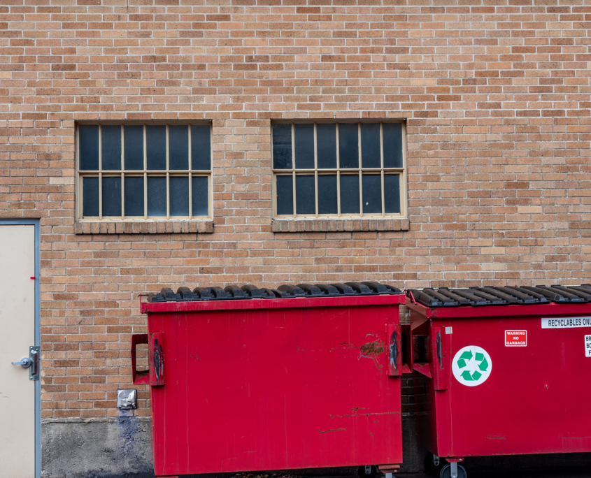 Red Dumpster And Recycling Container In The Back Behind Commercial Building