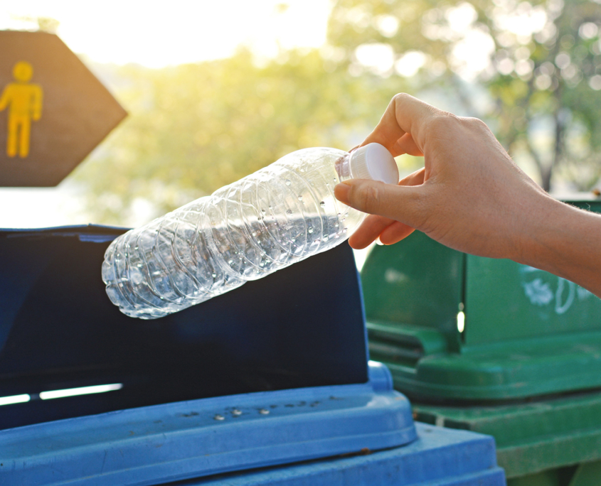 Close Up Of Hand Throwing Plastic Bottle In Reyccling Bin