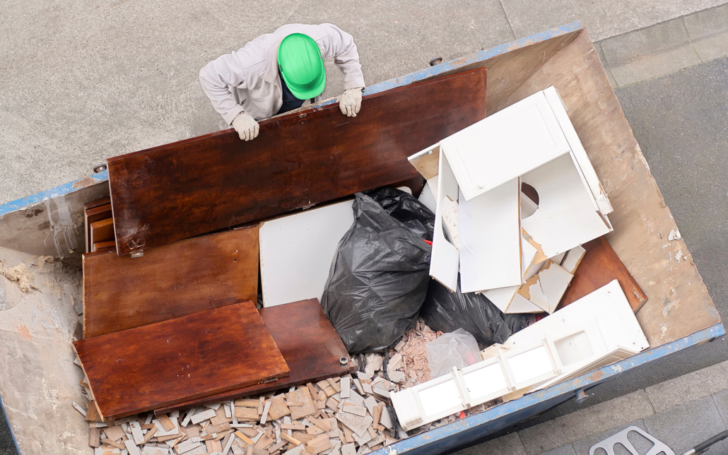 Top Down View Of Man Looking Into Dumpster Filled With Debris